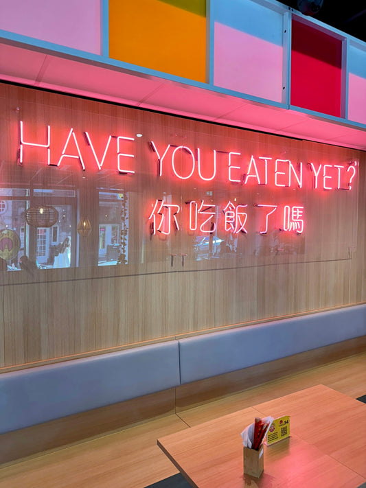 a restaurant with a neon sign that says have you eaten yet?