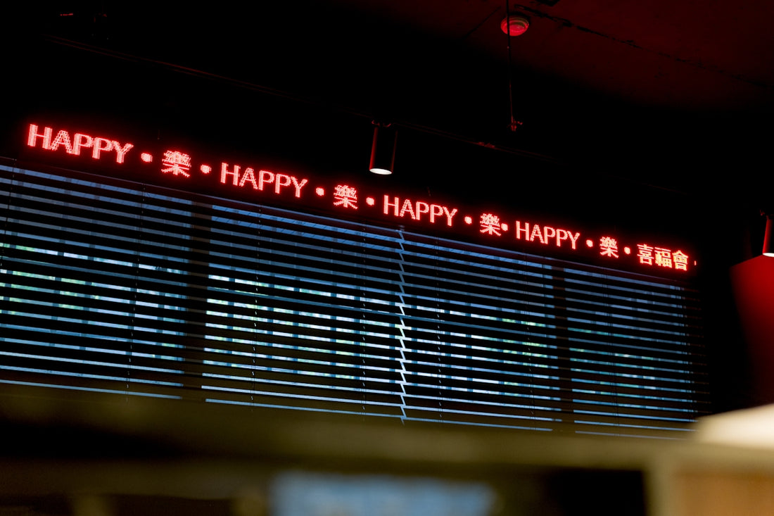 Red led sign displays the word happy repeated.