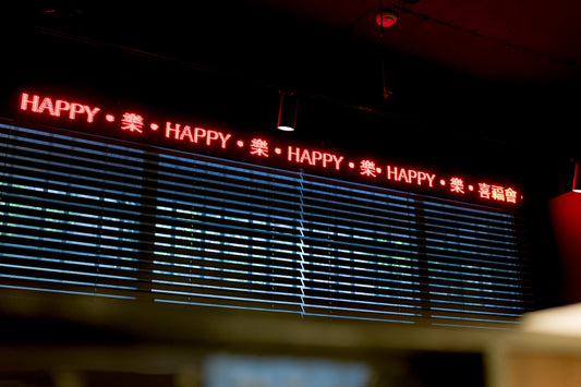 Red led sign displays the word happy repeated.