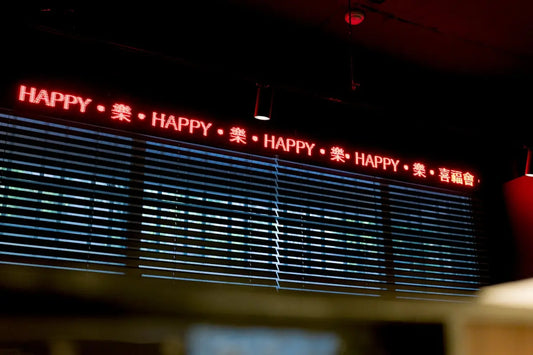 Red led sign displays the word happy repeated.